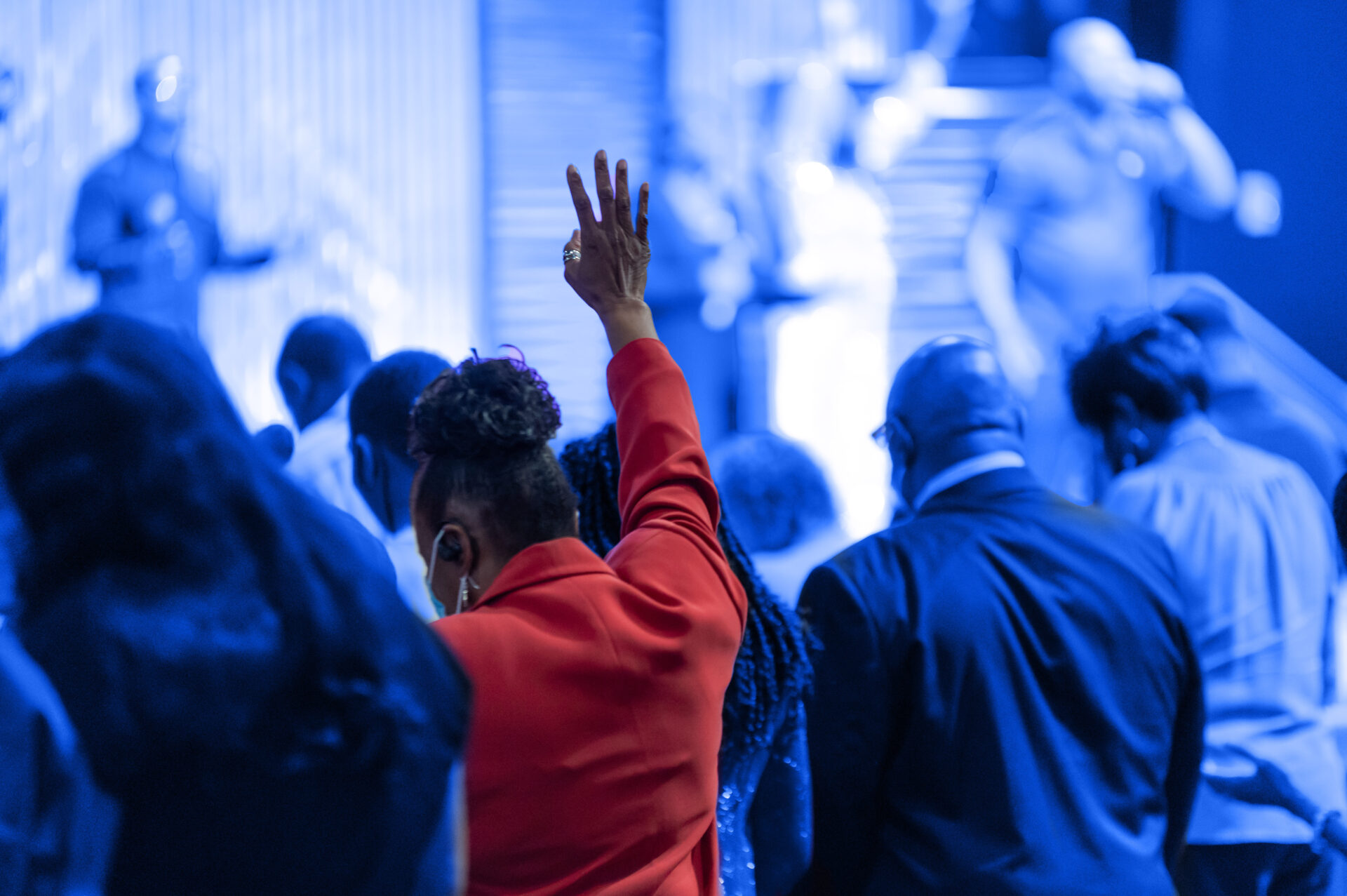 woman in congregation with arm raised